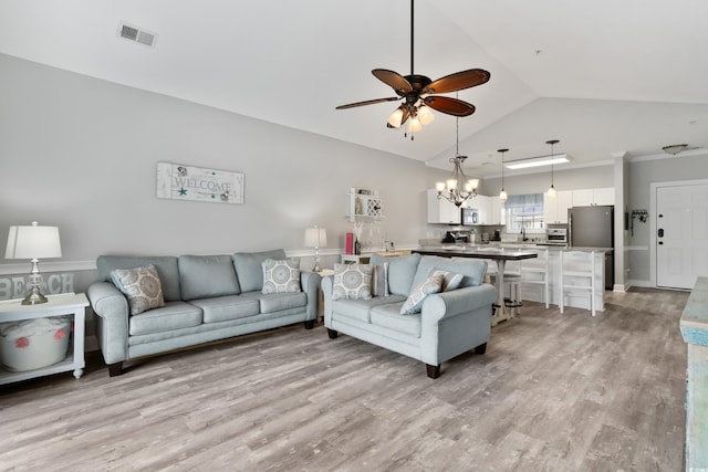 living area featuring light wood-type flooring, visible vents, vaulted ceiling, and ceiling fan with notable chandelier