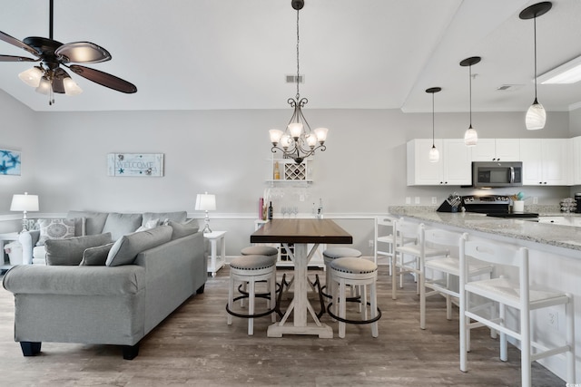 living area featuring visible vents, dark wood finished floors, and ceiling fan with notable chandelier