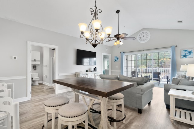 dining area featuring light wood finished floors, baseboards, visible vents, vaulted ceiling, and a chandelier