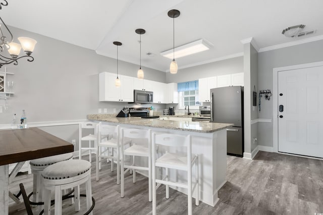 kitchen featuring a peninsula, white cabinetry, stainless steel appliances, and decorative light fixtures