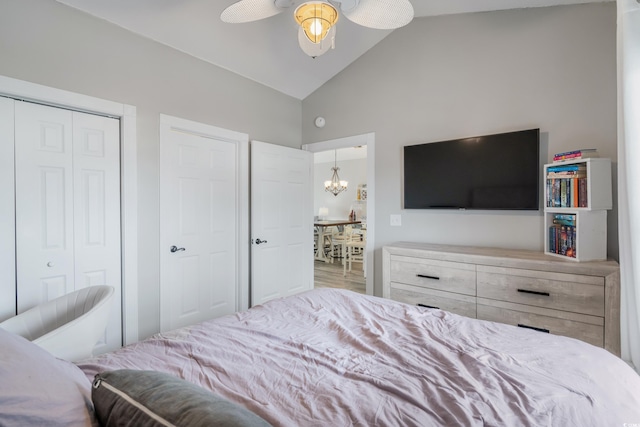 bedroom with lofted ceiling, a closet, and ceiling fan with notable chandelier