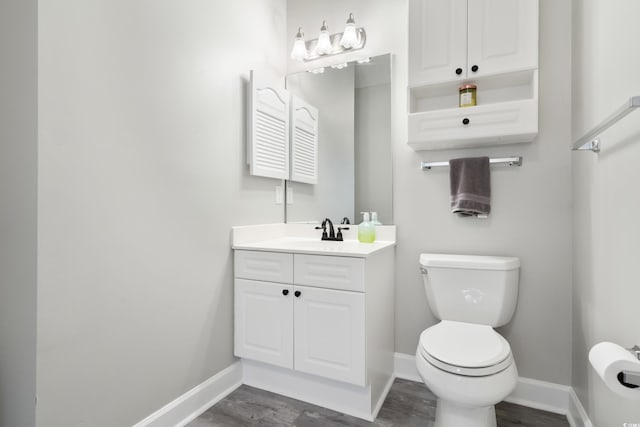 bathroom featuring toilet, baseboards, wood finished floors, and vanity