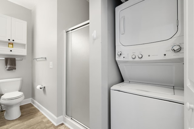 clothes washing area with laundry area, light wood finished floors, stacked washing maching and dryer, and baseboards