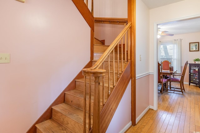 staircase featuring wood-type flooring, beverage cooler, baseboards, and a ceiling fan