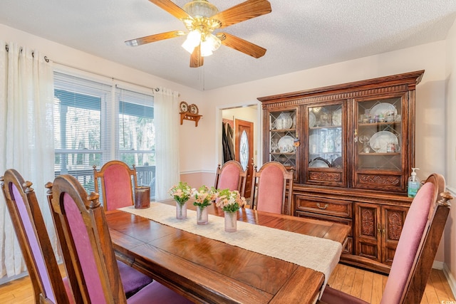 dining area with light wood-style flooring, a textured ceiling, and ceiling fan