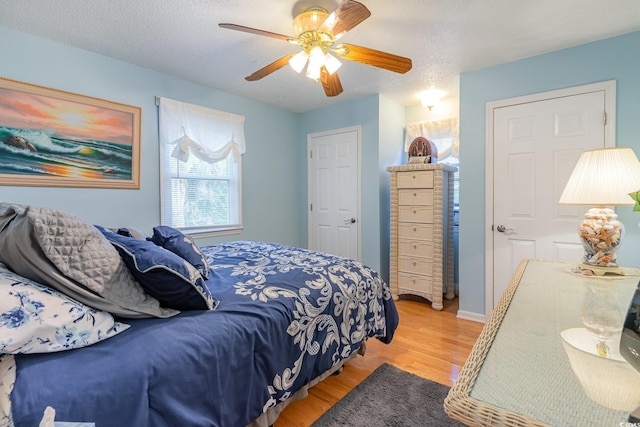 bedroom featuring baseboards, a textured ceiling, a ceiling fan, and wood finished floors