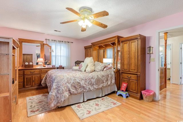 bedroom featuring visible vents, ceiling fan, light wood-type flooring, and a textured ceiling