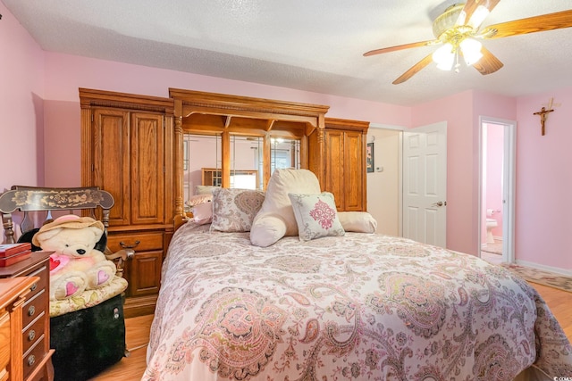 bedroom featuring ensuite bathroom, a textured ceiling, a ceiling fan, light wood finished floors, and baseboards