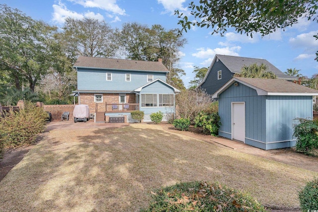 rear view of house with a shed, brick siding, a wooden deck, an outbuilding, and a lawn