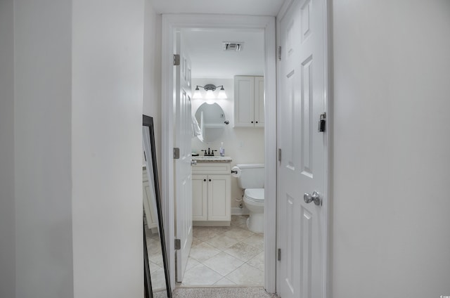 half bath featuring toilet, tile patterned floors, visible vents, and vanity