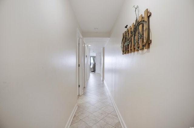 corridor featuring light tile patterned floors and baseboards