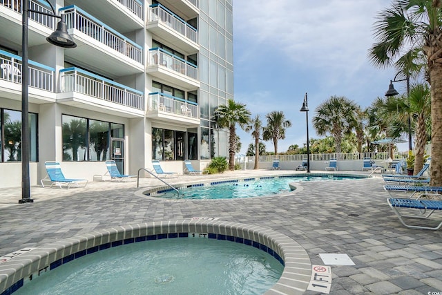 view of swimming pool with a community hot tub, a patio area, and fence