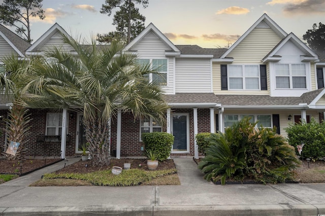 multi unit property with roof with shingles and brick siding