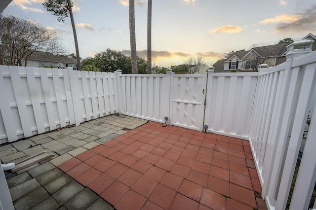 patio terrace at dusk featuring fence and a gate