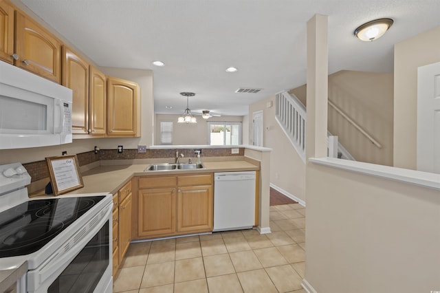 kitchen with white appliances, light tile patterned floors, visible vents, a peninsula, and a sink