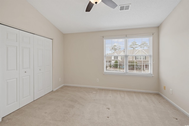 unfurnished bedroom featuring carpet, a closet, visible vents, a textured ceiling, and baseboards