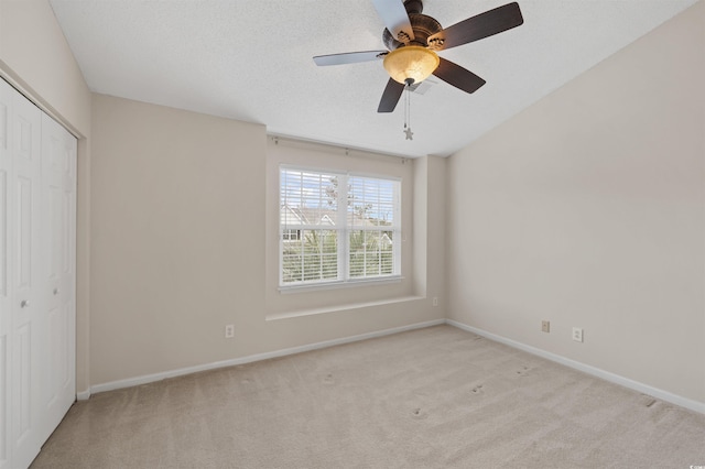 unfurnished bedroom with a textured ceiling, carpet flooring, a ceiling fan, baseboards, and a closet