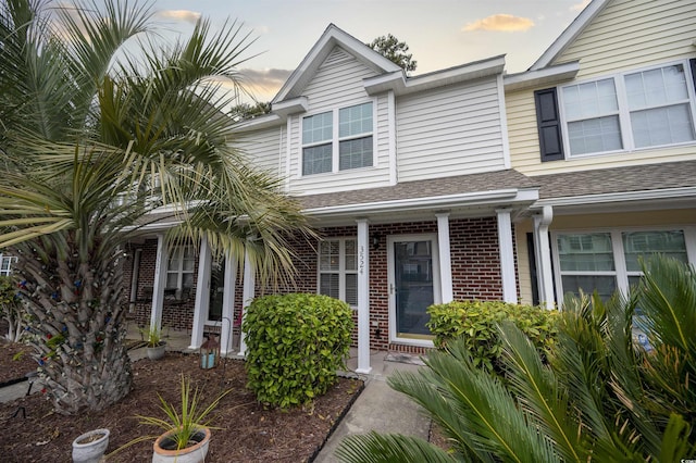 view of front of house with a shingled roof and brick siding