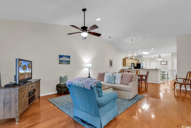 living room featuring high vaulted ceiling, light wood-style flooring, baseboards, and ceiling fan with notable chandelier