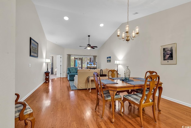 dining space featuring high vaulted ceiling, light wood-style flooring, recessed lighting, ceiling fan with notable chandelier, and baseboards