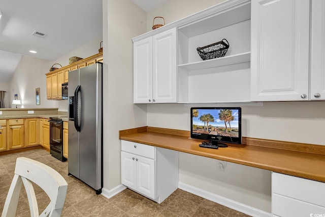 kitchen with black / electric stove, visible vents, white cabinets, built in study area, and stainless steel fridge with ice dispenser