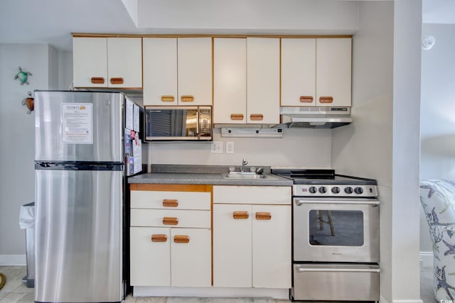 kitchen with stainless steel appliances, dark countertops, a sink, and under cabinet range hood