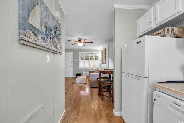 kitchen with white appliances, ornamental molding, white cabinets, and light wood-style floors