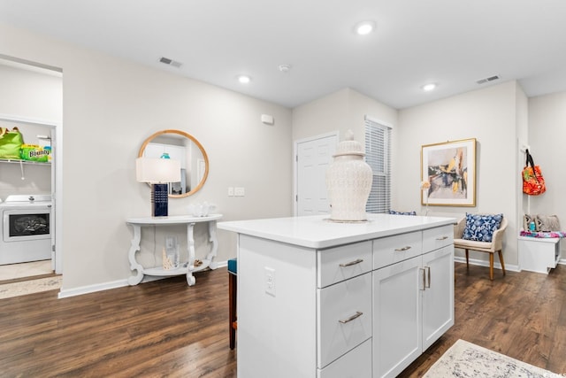 kitchen with visible vents, white cabinets, light countertops, a center island, and washer / clothes dryer