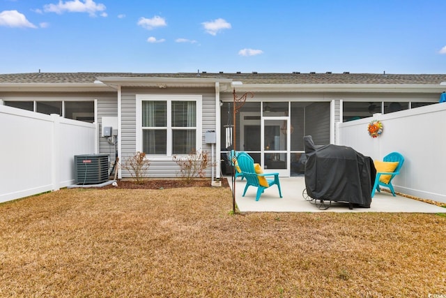 rear view of property featuring a yard, a patio, a sunroom, central AC, and a fenced backyard