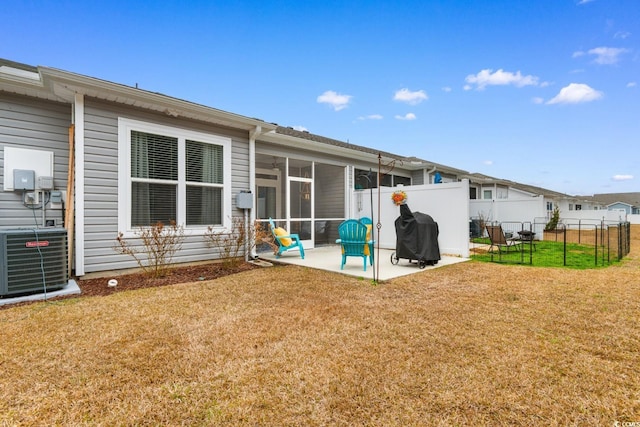 rear view of property with a yard, a patio, a sunroom, central AC, and fence