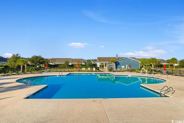 community pool with a patio area and fence