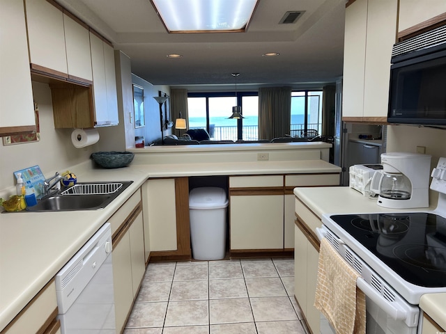 kitchen featuring light tile patterned floors, light countertops, white appliances, and a sink