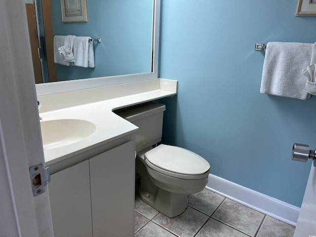 half bathroom with toilet, baseboards, vanity, and tile patterned floors