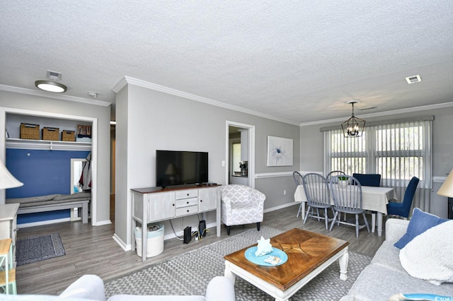 living area with visible vents, a textured ceiling, an inviting chandelier, and wood finished floors