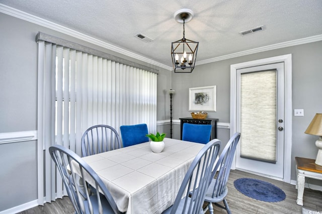 dining area with dark wood-style floors, visible vents, ornamental molding, and a textured ceiling