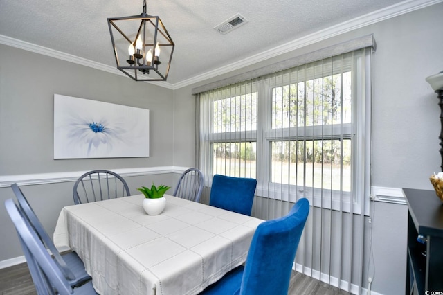 dining space featuring dark wood-style floors, visible vents, ornamental molding, a textured ceiling, and a chandelier