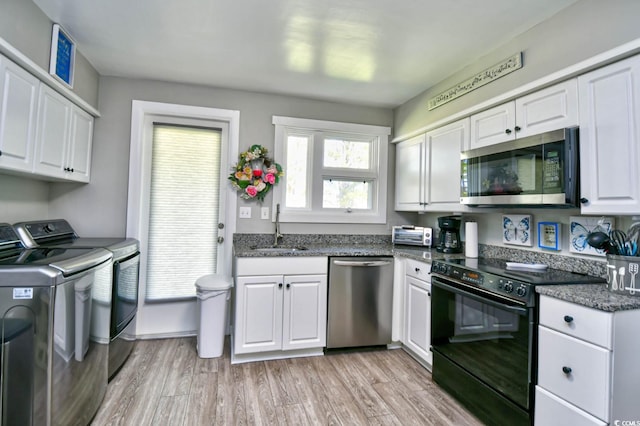 kitchen with washer and clothes dryer, appliances with stainless steel finishes, light wood-style floors, white cabinetry, and a sink