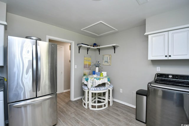 kitchen with washer / clothes dryer, white cabinetry, freestanding refrigerator, open shelves, and light wood finished floors