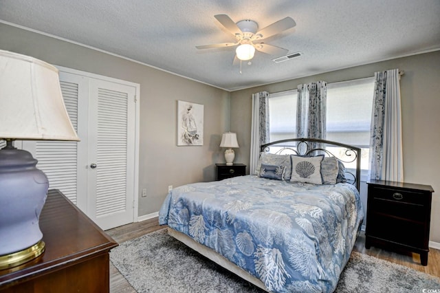 bedroom with light wood-type flooring, a textured ceiling, visible vents, and a closet