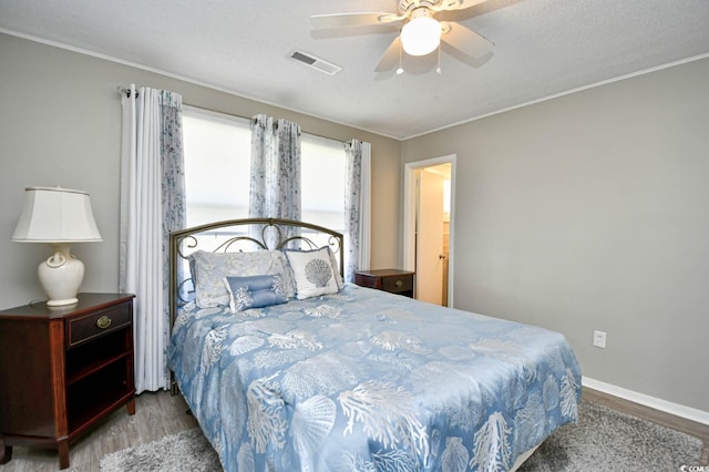 bedroom featuring baseboards, a textured ceiling, visible vents, and wood finished floors