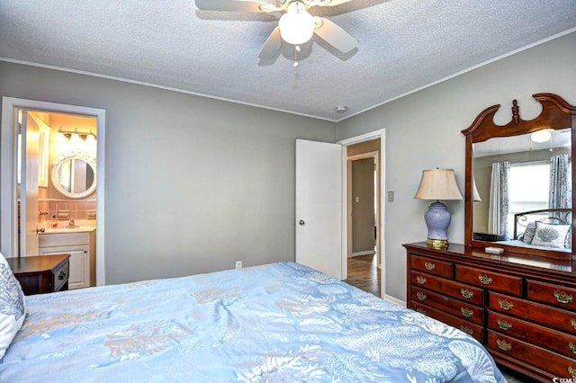 bedroom with crown molding, a textured ceiling, ensuite bath, and ceiling fan