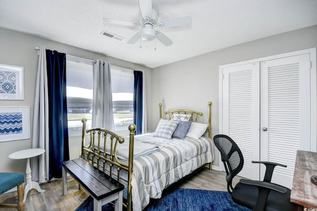 bedroom with a ceiling fan, a closet, visible vents, and wood finished floors