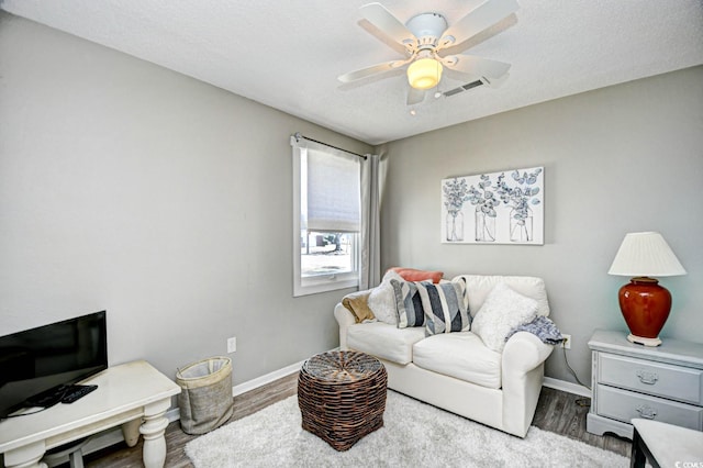 office space featuring baseboards, visible vents, a ceiling fan, wood finished floors, and a textured ceiling