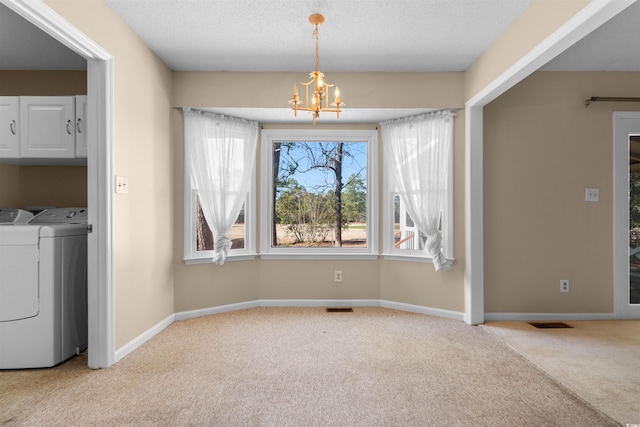 unfurnished dining area with light carpet, baseboards, visible vents, washer and dryer, and a chandelier