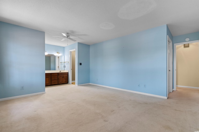 unfurnished bedroom featuring light carpet, connected bathroom, baseboards, and a textured ceiling