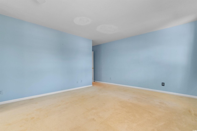 unfurnished room with baseboards and light colored carpet