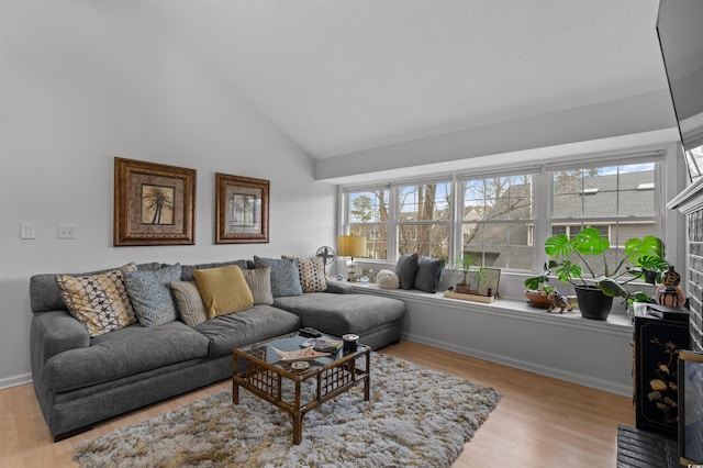 living room featuring baseboards, high vaulted ceiling, wood finished floors, and a healthy amount of sunlight