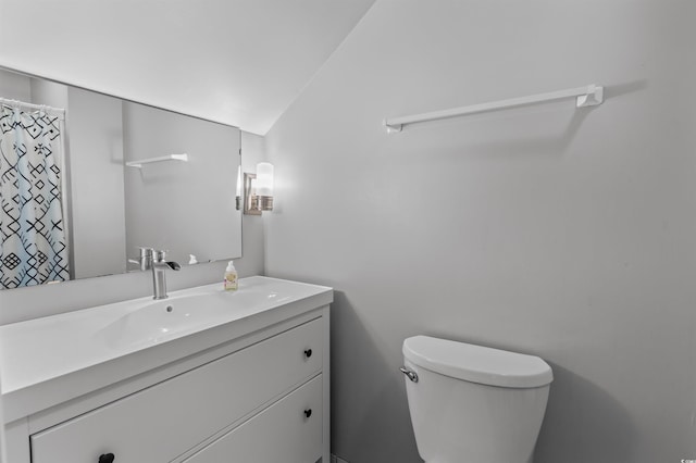 bathroom with lofted ceiling, vanity, and toilet