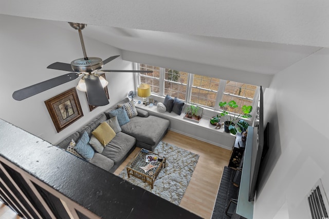 living area with lofted ceiling, baseboards, a ceiling fan, and wood finished floors