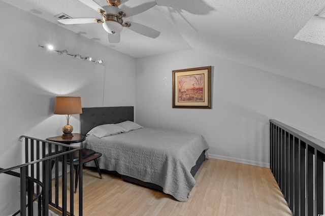 bedroom featuring lofted ceiling, ceiling fan, a textured ceiling, and wood finished floors